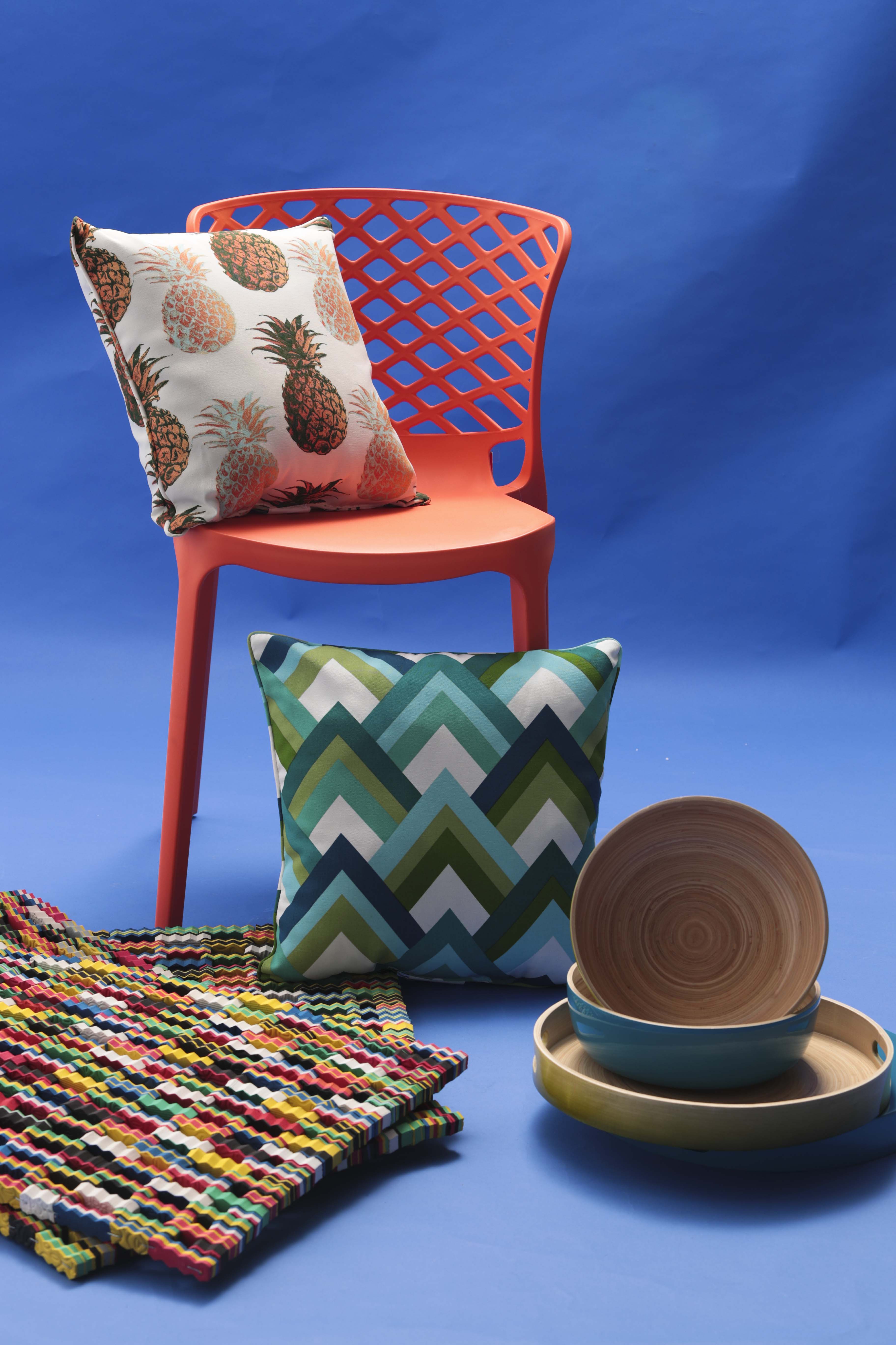 Silla de plástico con respaldo trenzado y bandejas de bambú laminado, de Aliss; cojín con estampado de piña, cojín estampado con diseños triangulares y alfombras confeccionadas con suelas de chancletas recicladas, de Bed, Bath and Beyond. (Foto Wanda LIz Vega)