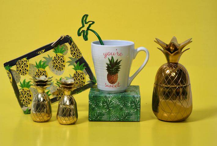 Cartera pequeña, transparente, con estampado de piñas, de Macy’s; “shot glasses” dorados, de Macy’s; taza, de Macy’s; pieza decorativa en madera y bronce, de TJ Max; y pieza decorativa dorada en forma de piña, de Macy’s.