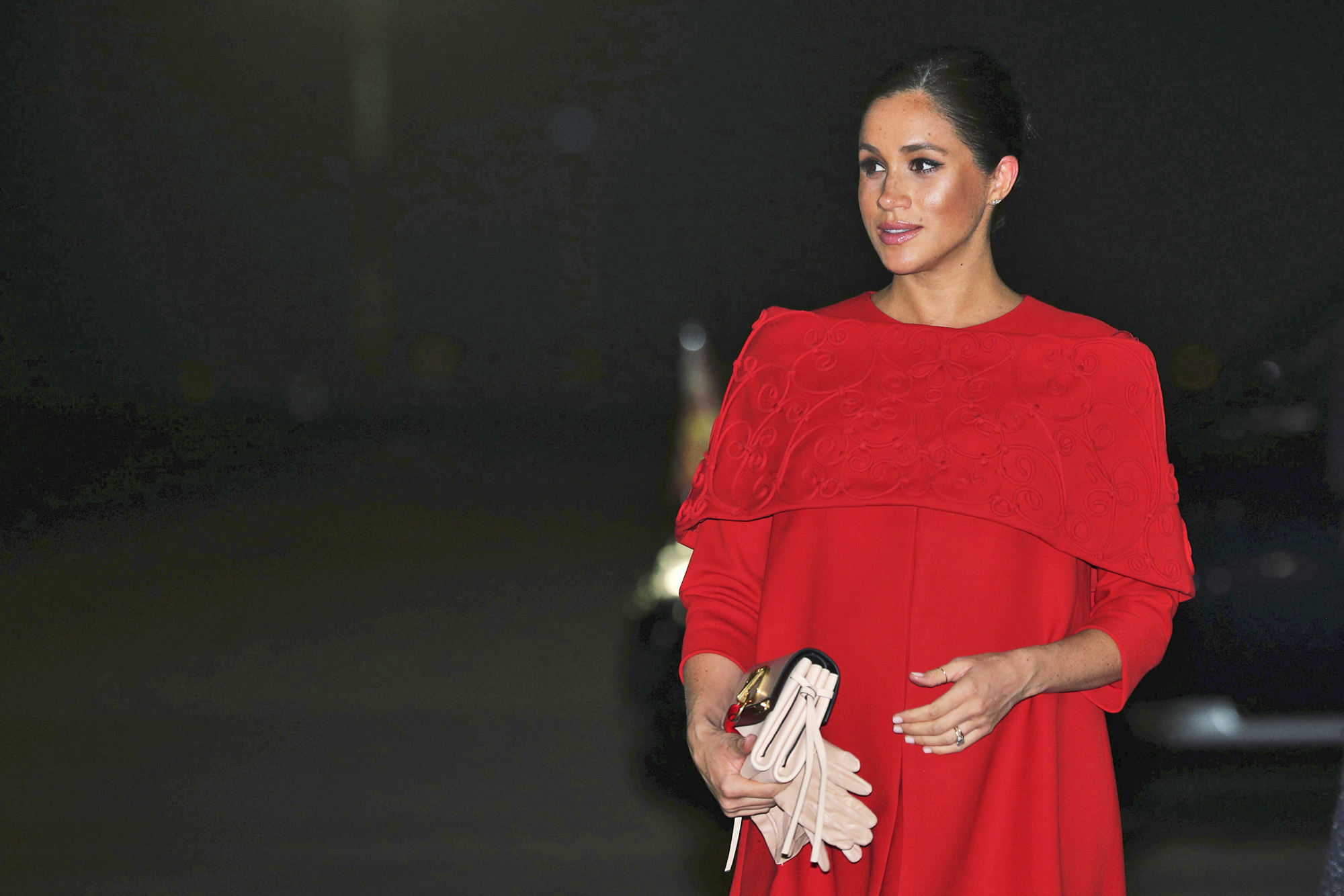Meghan optó por un vestido rojo de Valentino por encima de las rodillas, con una discreta capa bordada y con un corte que marcaba su, ya abultada barriguita. (AP)