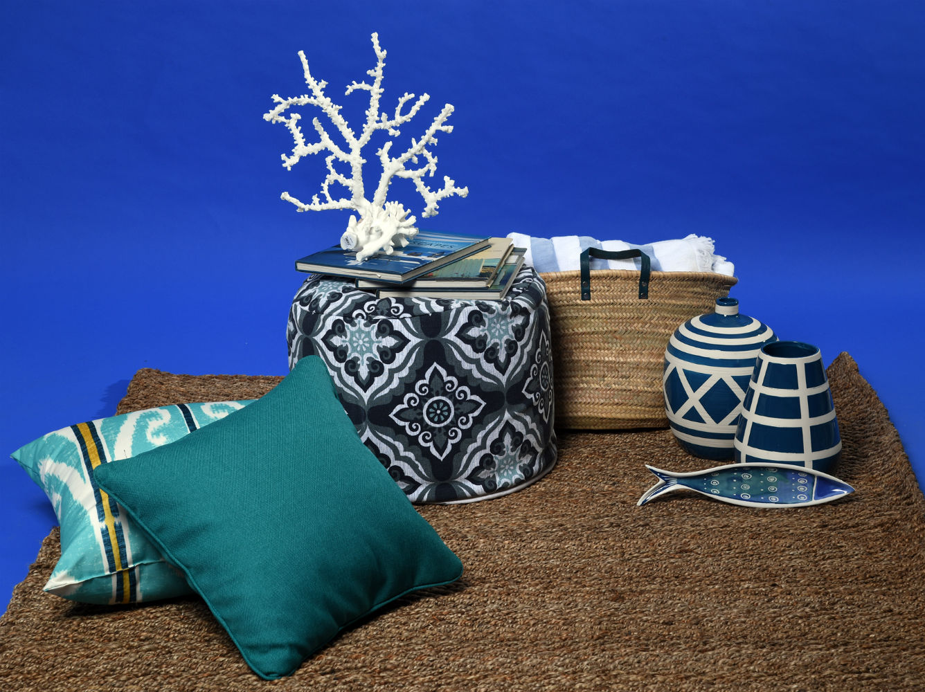 “Pouf”, jarrones y plato de cerámica en forma de pez, de Aliss; imitación de coral, cojín estampado y alfombra de fibra natural, de Pottery Barn; cojín turquesa, de Cantópa; cartera de paja y toalla, de Aaron Stewart Home. (André Kang)