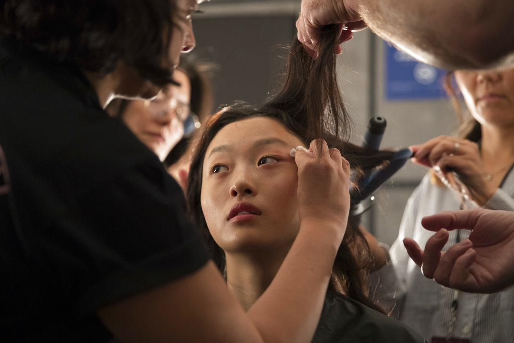 Un maquillista trabaja sobre el rostro de una modelo antes de presentar la colección primavera/verano 2019 de Milly. (Foto: AP)