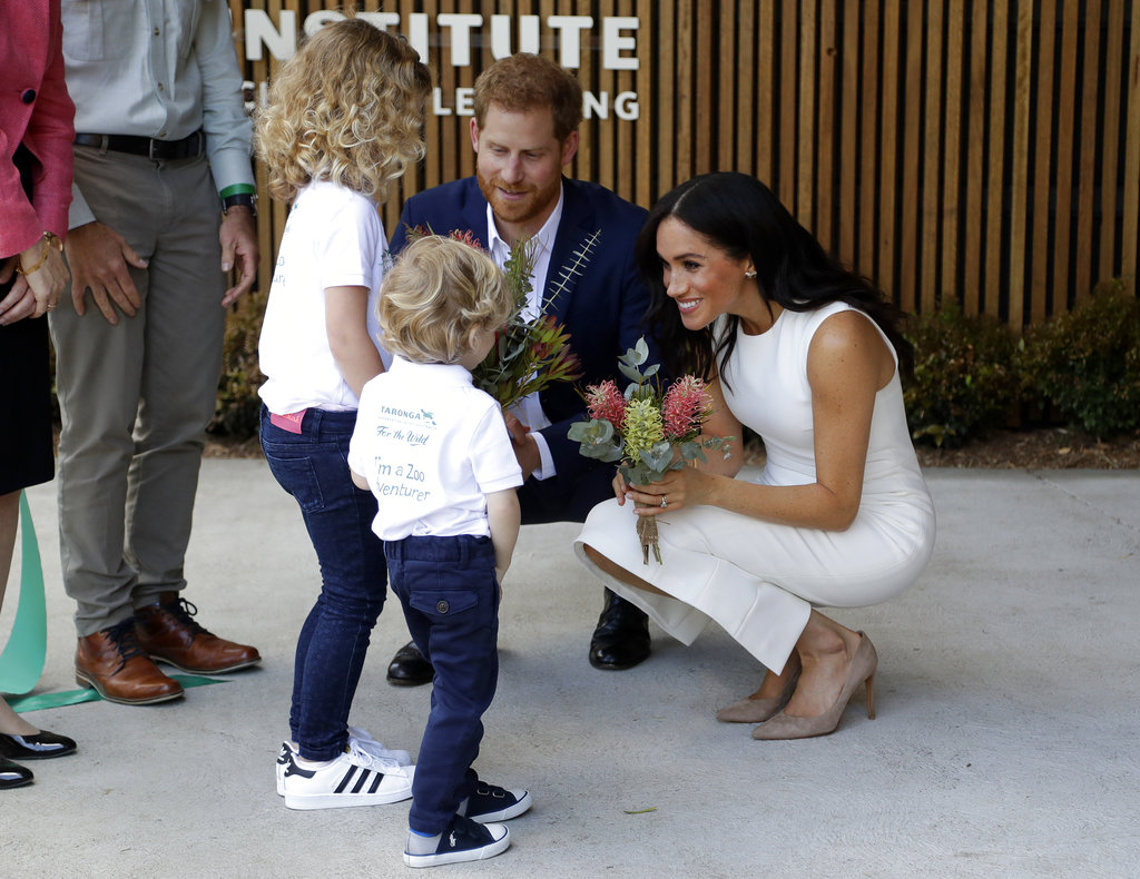 El príncipe Harry y Meghan Markle reciben un ramo de flores de manos de Finley Blue and Dasha Gallagher en el Taronga Zoo de Sidney, uno de los sitios que visitaron en Australia. (Foto: AP)