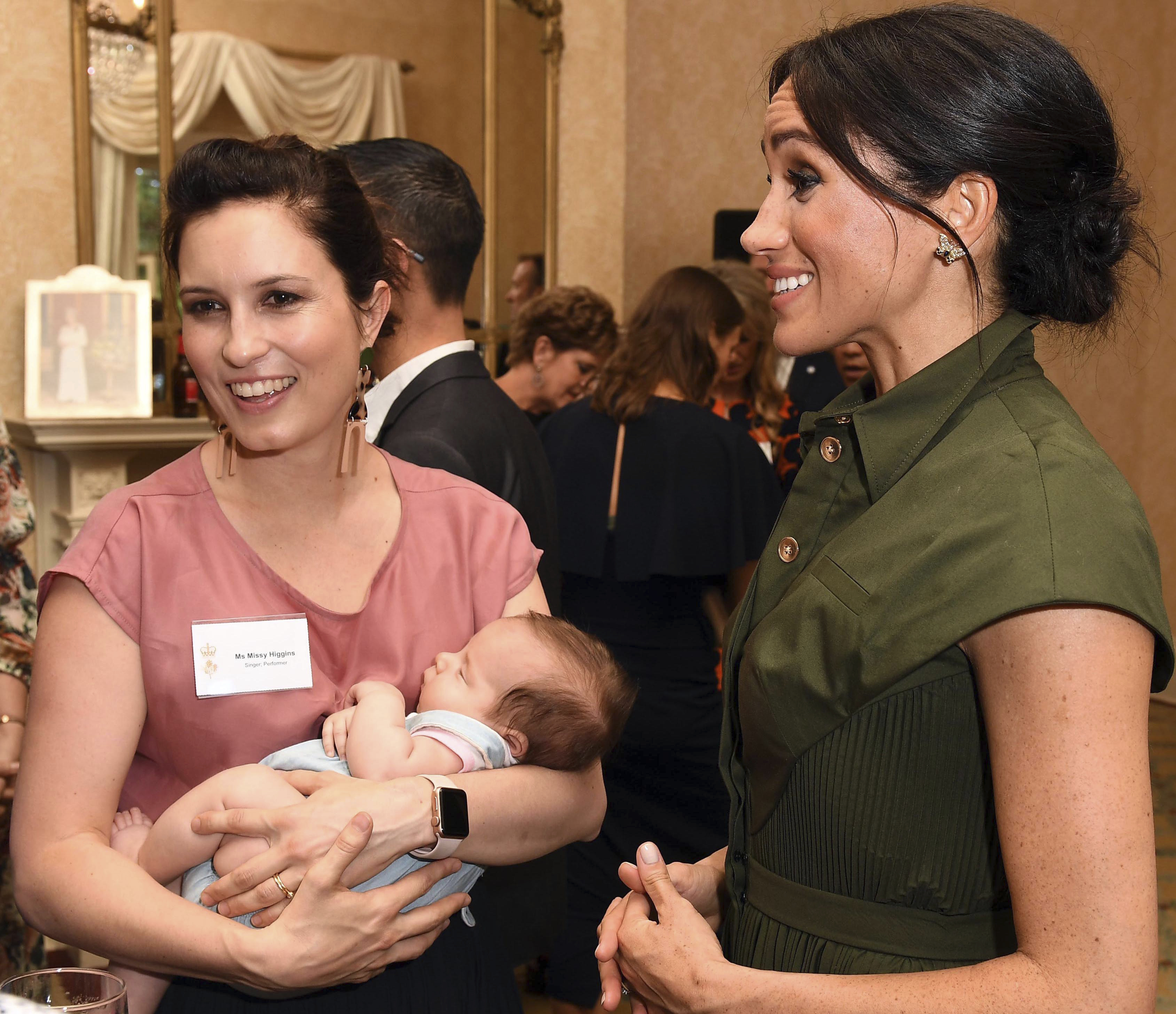 Meghan conversa con la cantante australiana Missy Higgins, quien carga a su bebé de 9 meses durante una recepción ofrecida por el gobernador general de Australia. (Foto:AP)