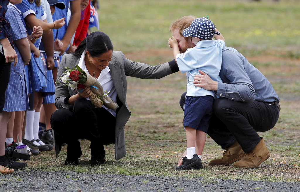 Luke Vincent, de 5 años, juega con la nariz del príncipe Harry mientras Meghan Markle tiene un gesto de cariño con los dos a su llegada a Dubbo, Australia. (Foto: AP)