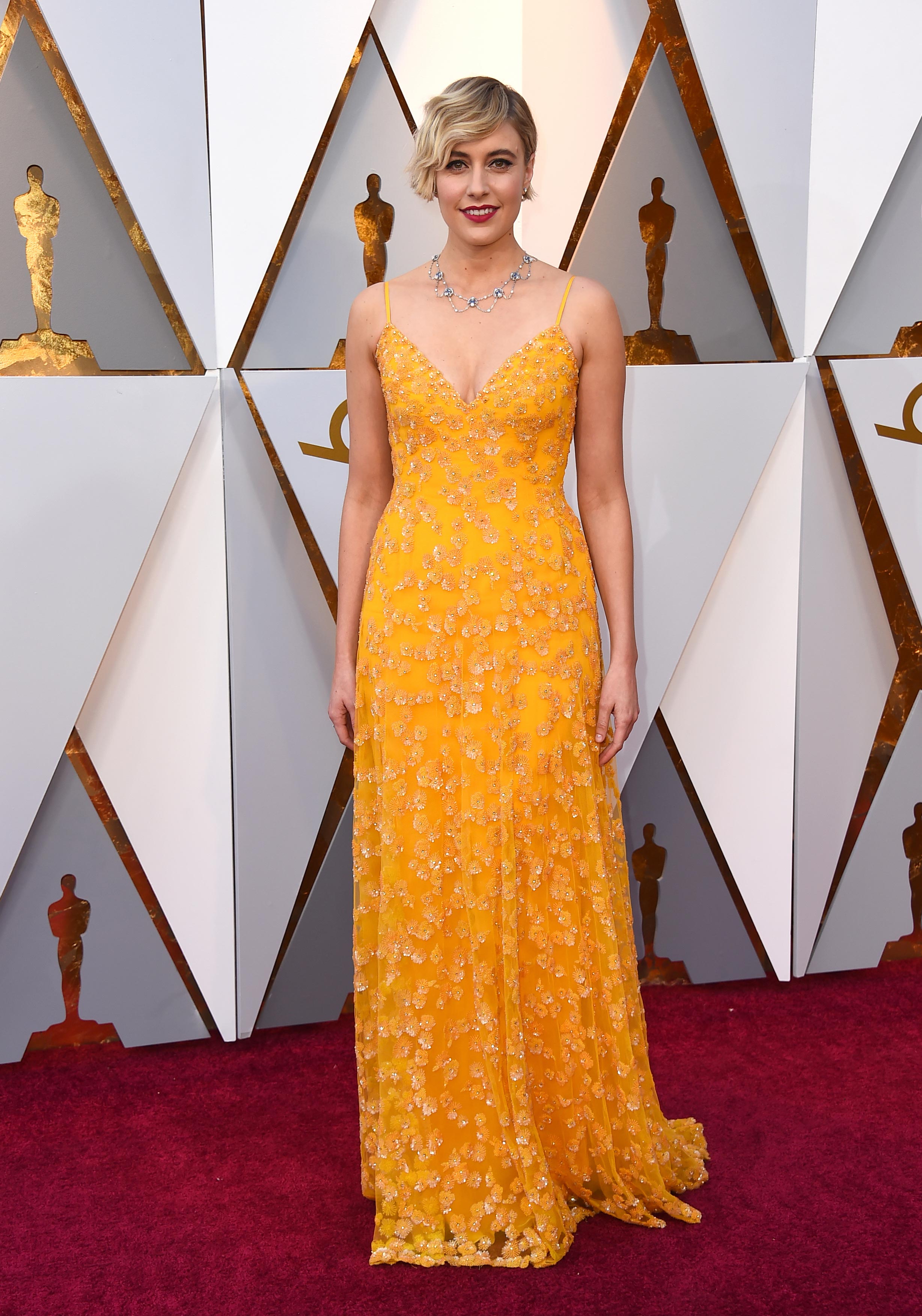 Greta Gerwig, nominada al Oscar en las categorías Mejor director y Mejor guión original, luce un vestido en tono amarillo intenso de Rodarte , uno de los colores de 2018. (The Associated Press)
