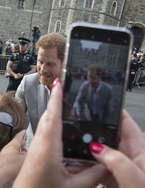 Un espectador retrata al Príncipe con su teléfono. (AP Photo/Peter Dejong)