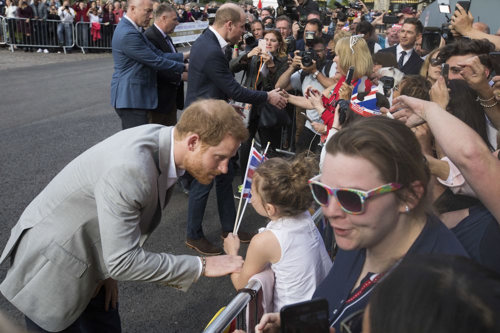 Haciendo gala de su buen humor y encanto, el príncipe Harry conversa con una niñita el día antes de la boda real. (AP Photo/Peter Dejong)