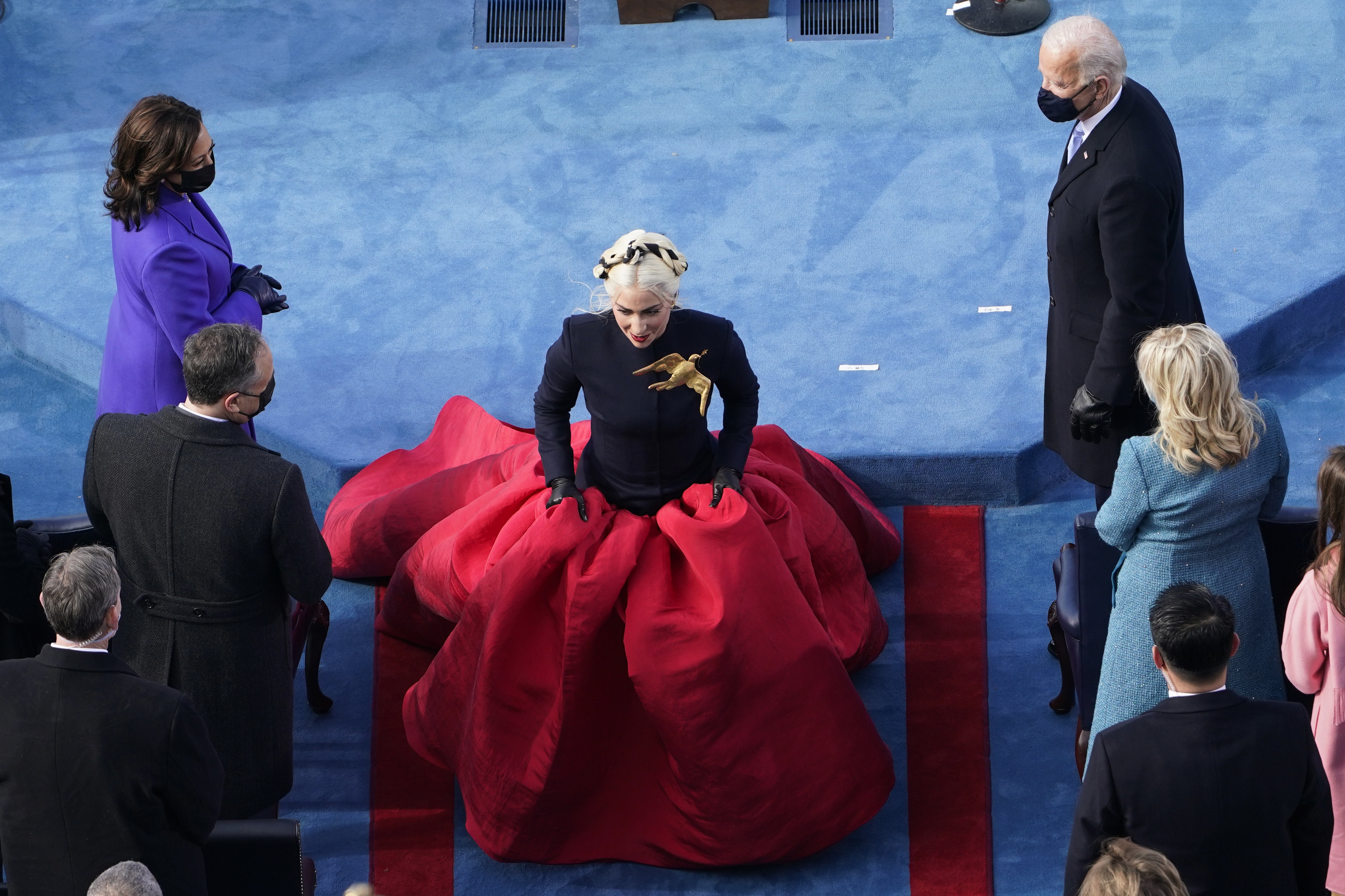 Lady Gaga cantó el himno nacional de Estados Unidos ataviada con un vestido compuesto por un top negro de cuello alto y mangas largas y una vaporosa falda roja de la casa Schiaparelli Couture. El toque más llamativo fue un broche dorado en forma de paloma que llevó sobre el lado izquierdo del pecho. (AP)