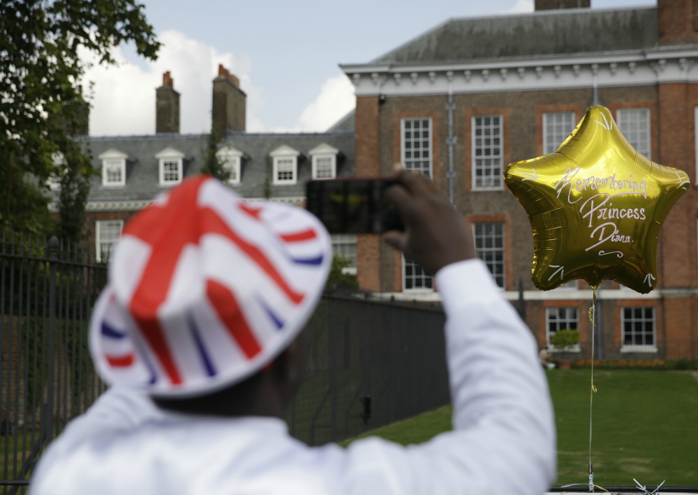 El admirador de la realeza, Joseph Afrane, toma una foto de un globo colocado junto a las puertas del Palacio de Kensington en Londres. (Foto: AP)