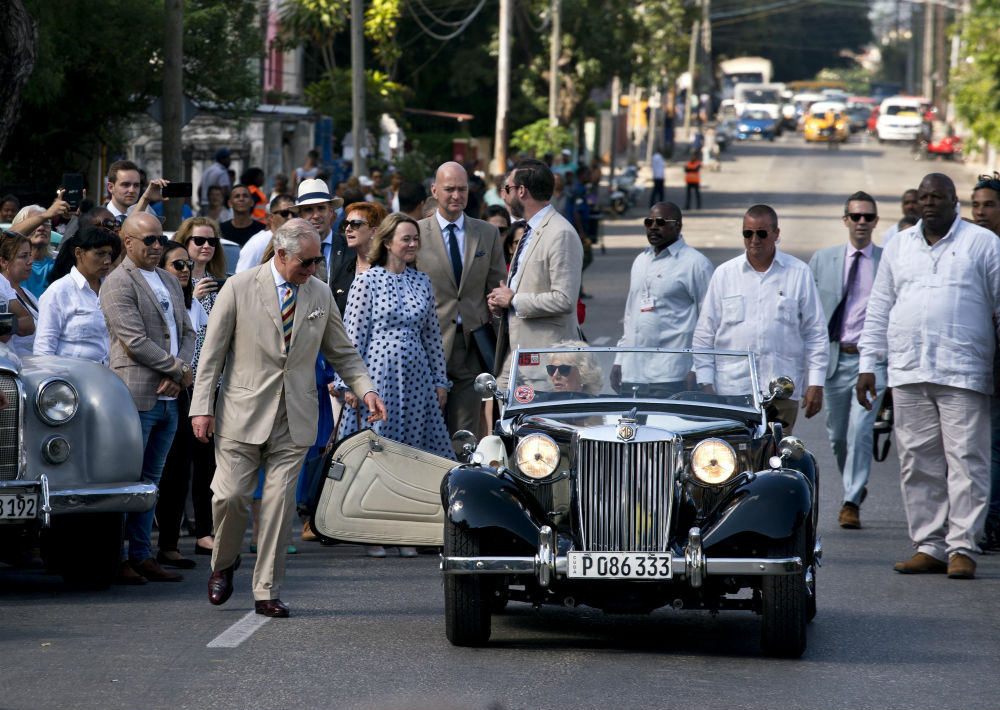 Charles iba vestido de traje crema y corbata rayada, y Camila, con vestido verde claro y resguardándose del intenso sol con su ya inseparable sombrilla blanca. (AP)