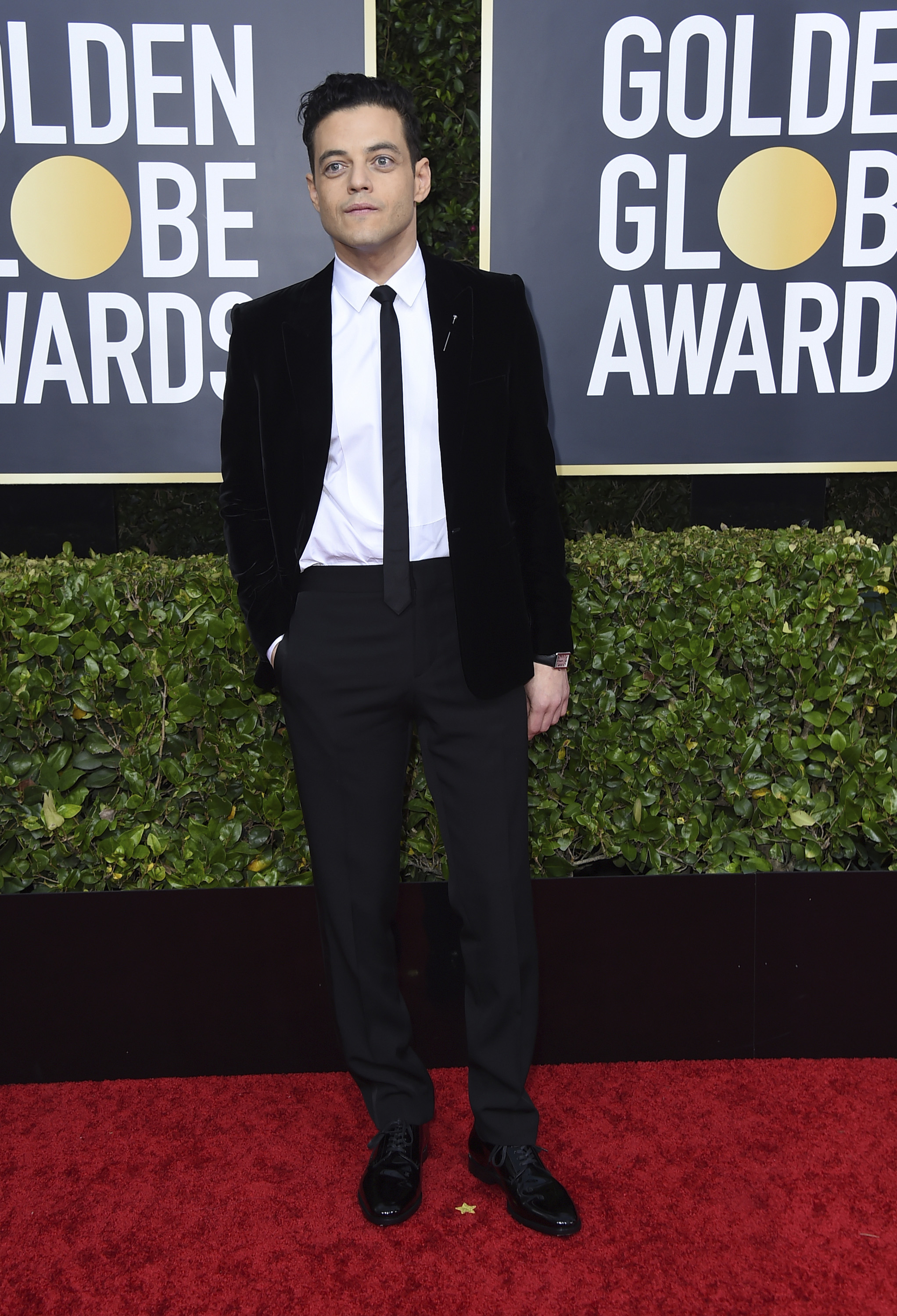 Rami Malek, de negro, con un entalle ültra skinny"y corbata estrecha, de Saint Laurent by Anthony Vaccarello y joyas Cartier. (AP)