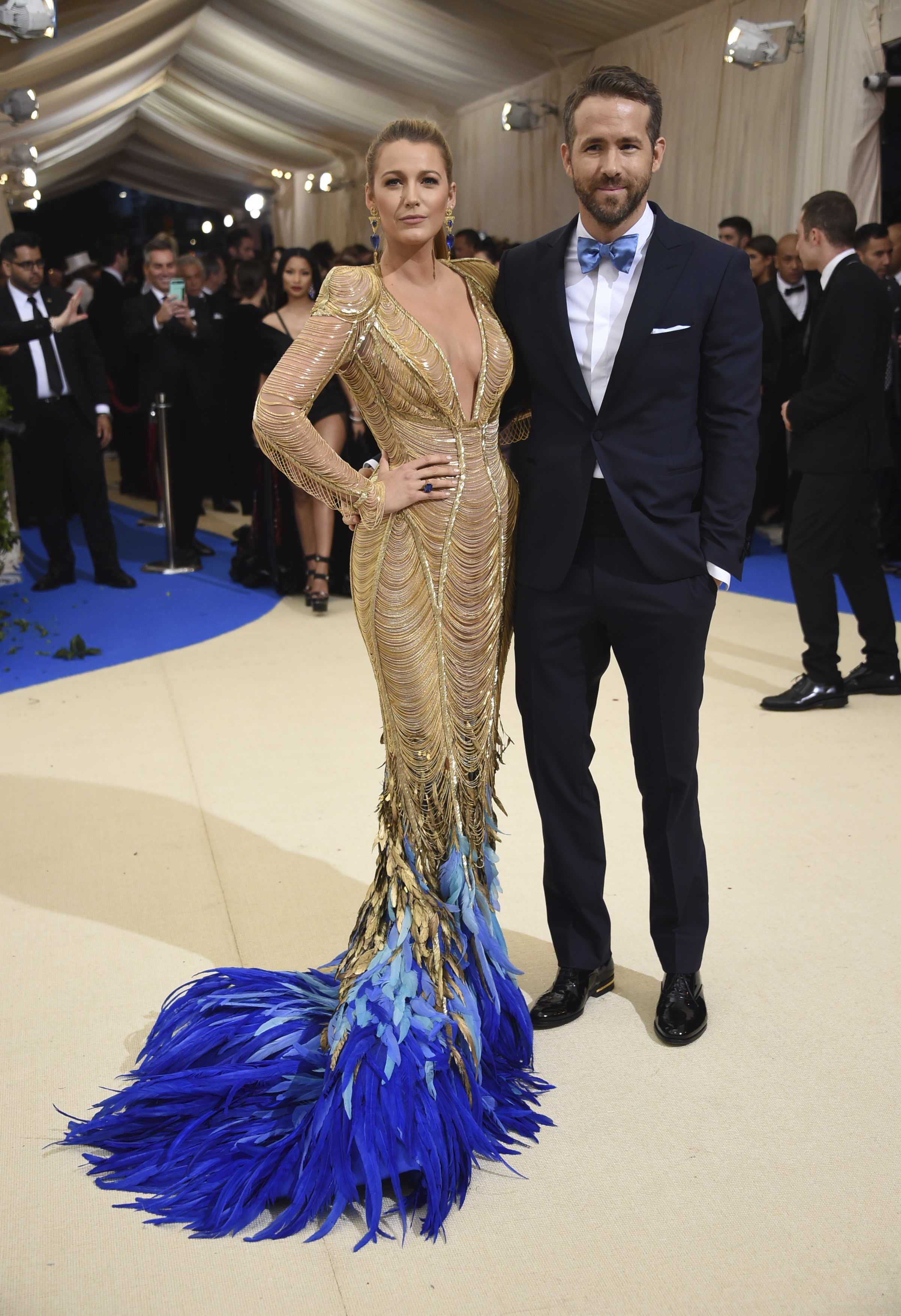 Blake Lively y Ryan Reynolds arrancaron suspiros a su llegada. Lively desfiló con un vestido dorado con una cauda adornada con plumas azules, cortesía de Versace. (AP / Evan Agostini / Invision)