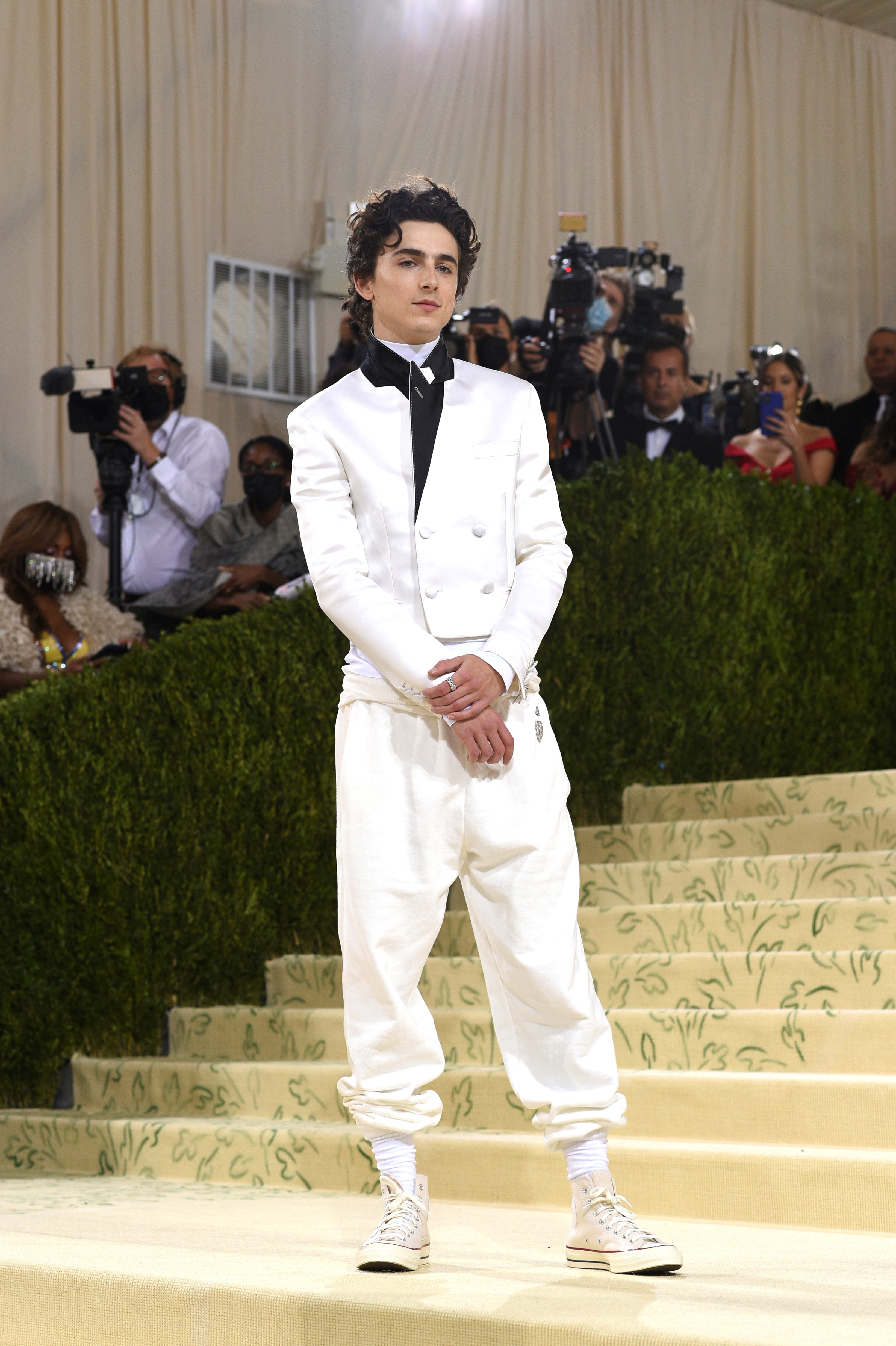 El actor Timothee Chalamet optó po un look del diseñador francés Haider Ackermann en blanco formado por una chaqueta de traje corta y pantalones jogger, que combinó con zapatillas Converse. (AP)
